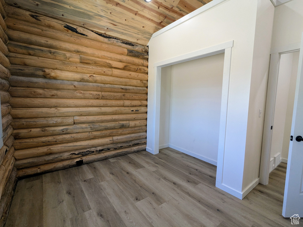 Unfurnished bedroom featuring log walls, wood ceiling, wood finished floors, and baseboards