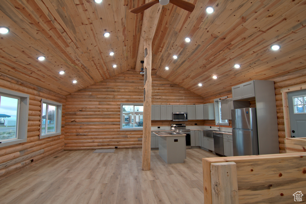 Kitchen with appliances with stainless steel finishes, log walls, gray cabinets, light wood-style flooring, and recessed lighting