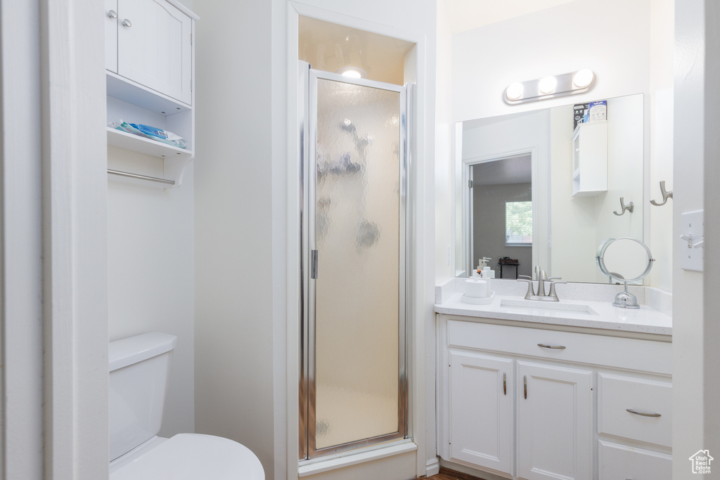 Full bath featuring vanity, a shower stall, and toilet