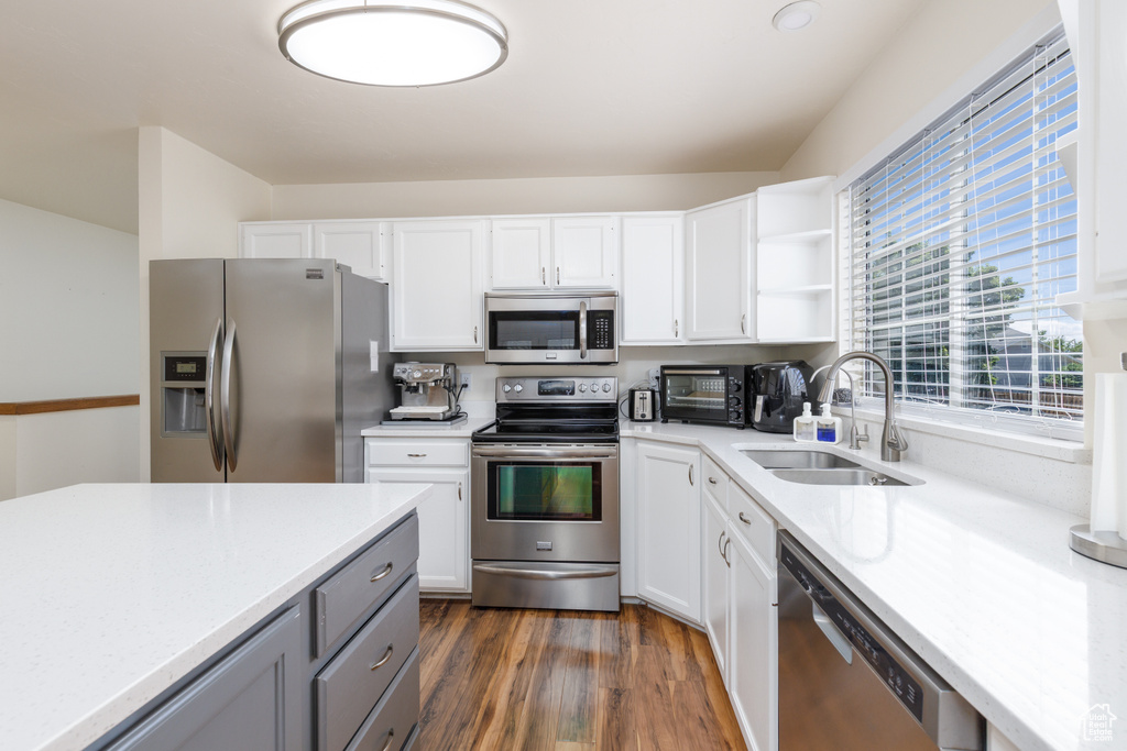 Kitchen with stainless steel appliances, a sink, light countertops, and white cabinets