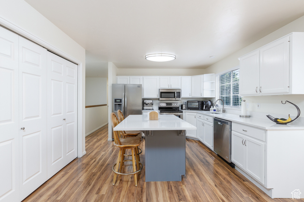 Kitchen featuring stainless steel appliances, a breakfast bar, and white cabinetry