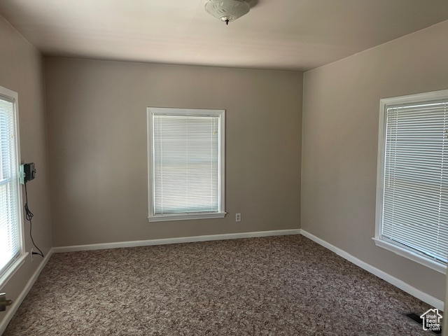 Unfurnished room featuring carpet flooring, healthy amount of natural light, and baseboards