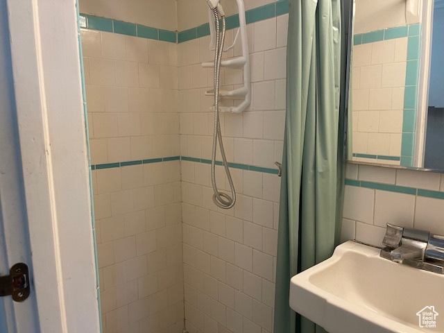 Bathroom with a sink, a tile shower, and tile walls