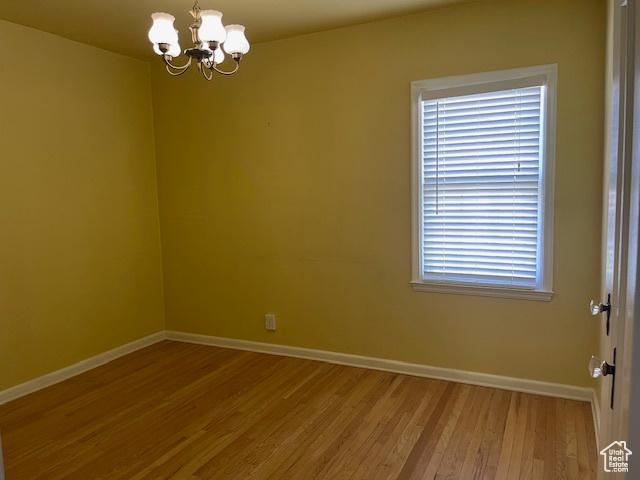 Unfurnished room with baseboards, a chandelier, and light wood finished floors