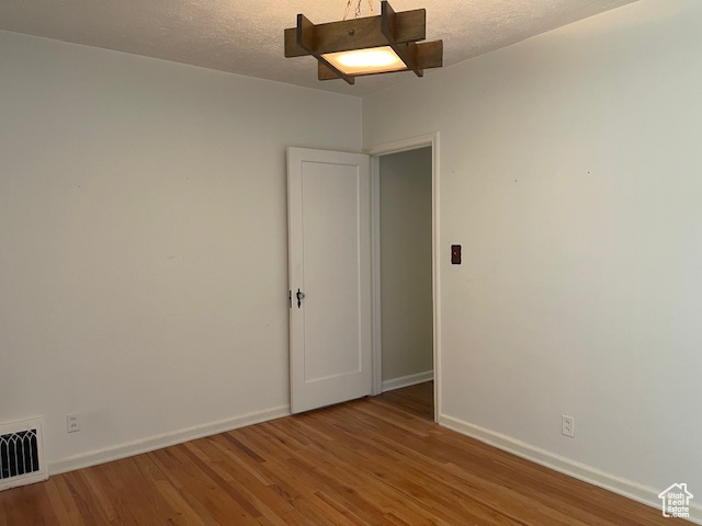 Spare room featuring wood finished floors, baseboards, and a textured ceiling