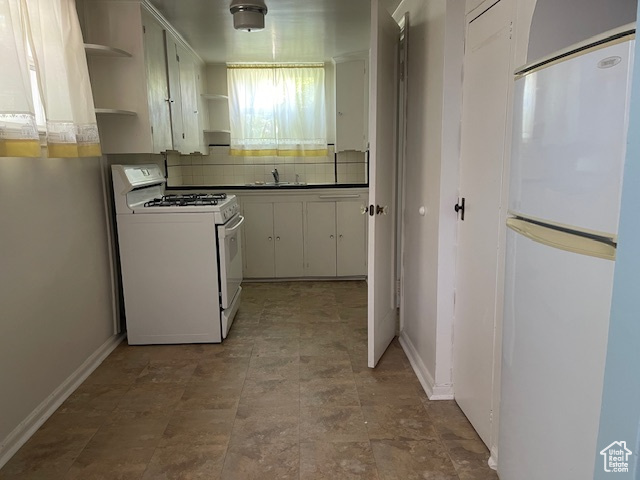 Kitchen with white gas range oven, refrigerator, open shelves, backsplash, and a sink