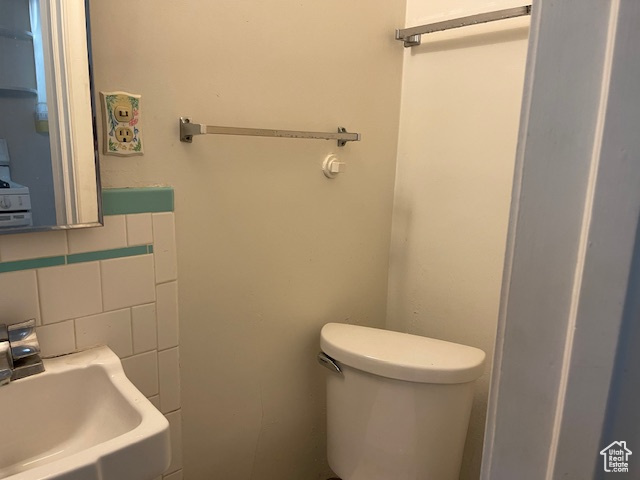 Half bath with a sink, toilet, and backsplash