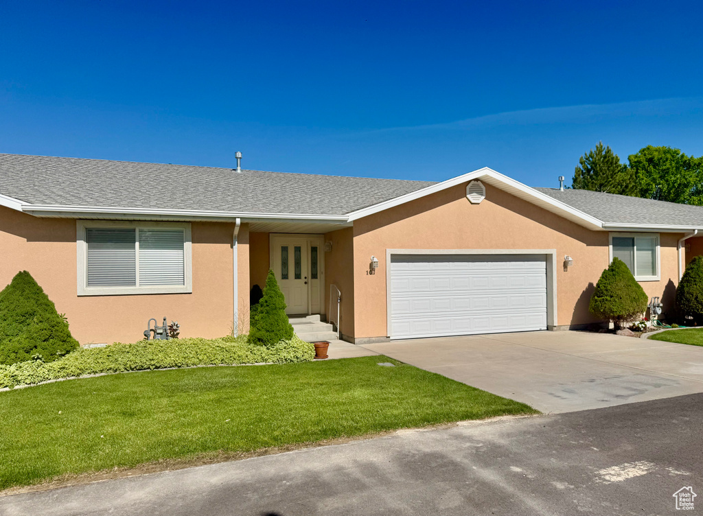 Ranch-style house with a front lawn, a garage, and stucco siding