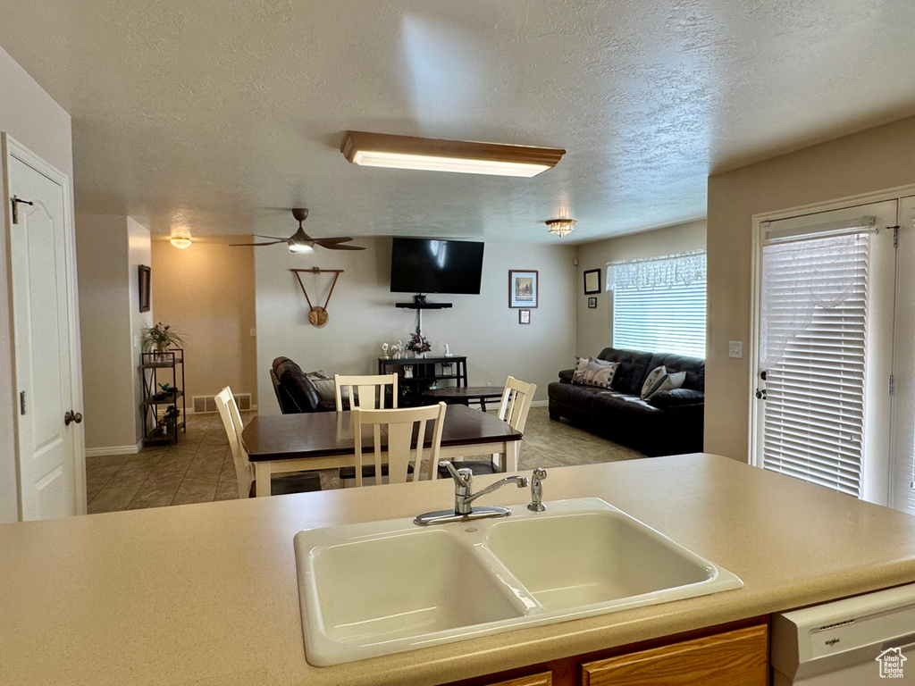 Kitchen with a sink, dishwasher, a textured ceiling, ceiling fan, and open floor plan