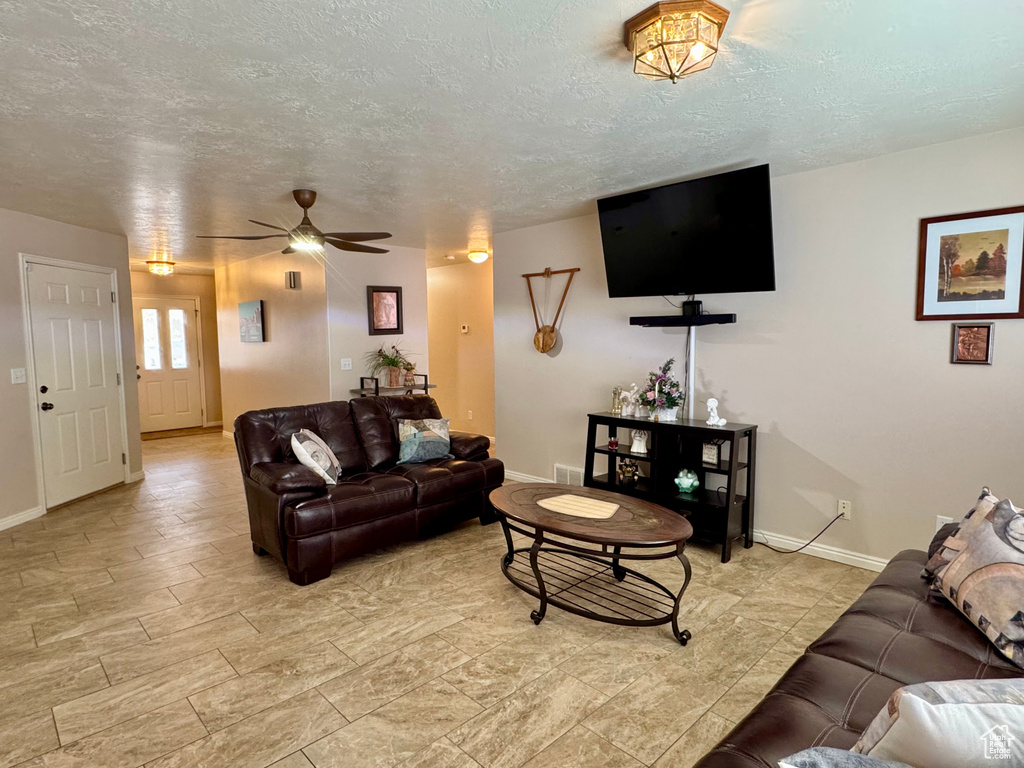 Living area featuring a ceiling fan, baseboards, and a textured ceiling
