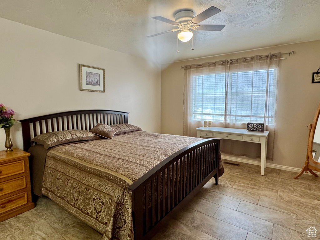 Bedroom with a textured ceiling and a ceiling fan