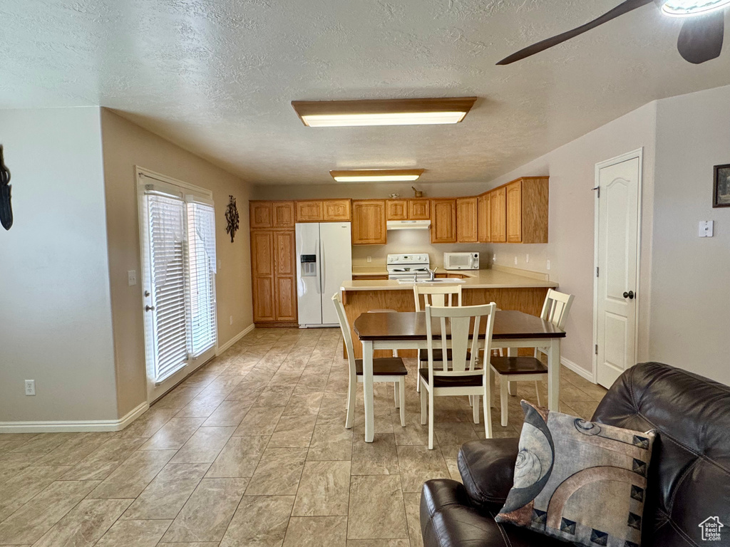 Kitchen with white appliances, ceiling fan, light countertops, a textured ceiling, and a peninsula