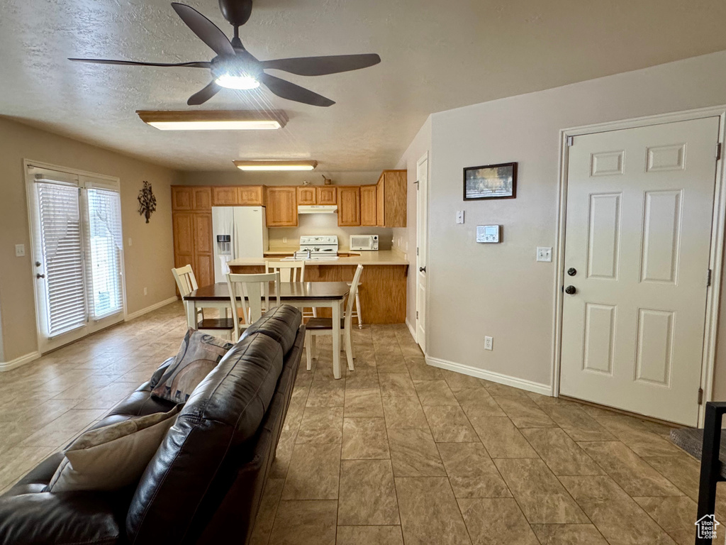Living area with ceiling fan and baseboards