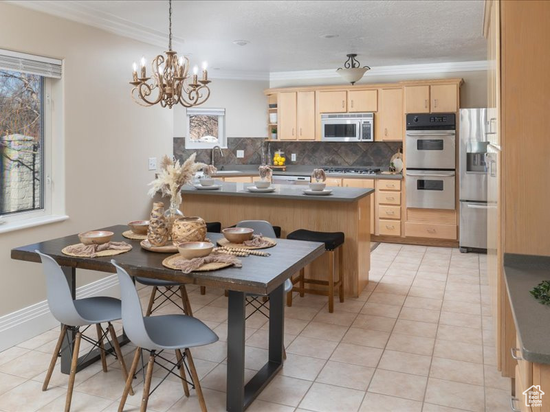 Kitchen featuring light brown cabinetry, stainless steel appliances, backsplash, crown molding, and a sink