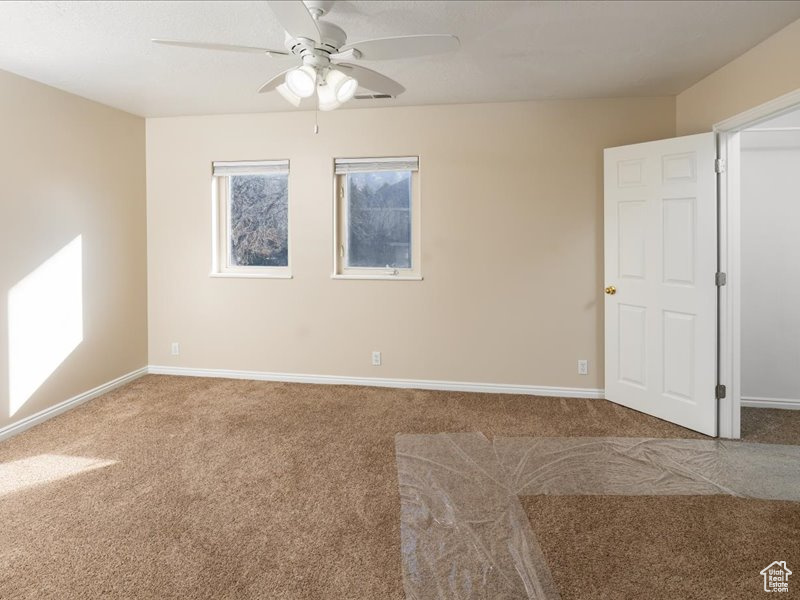 Spare room featuring carpet flooring, ceiling fan, and baseboards
