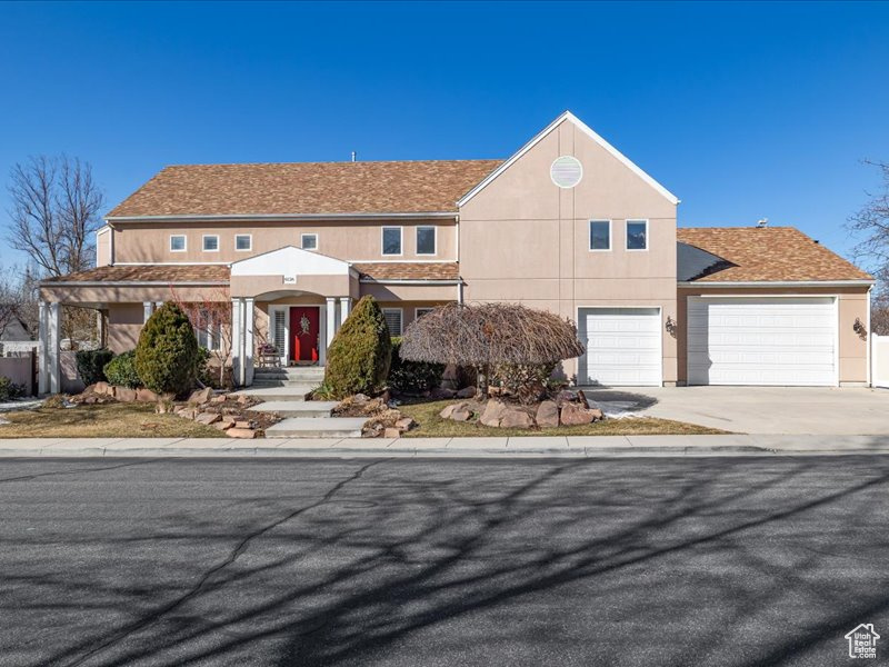 View of front facade with driveway, an attached garage, and stucco siding