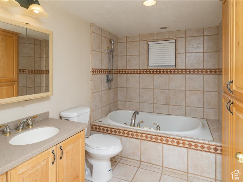 Bathroom with vanity, toilet, tiled shower / bath combo, and tile patterned floors