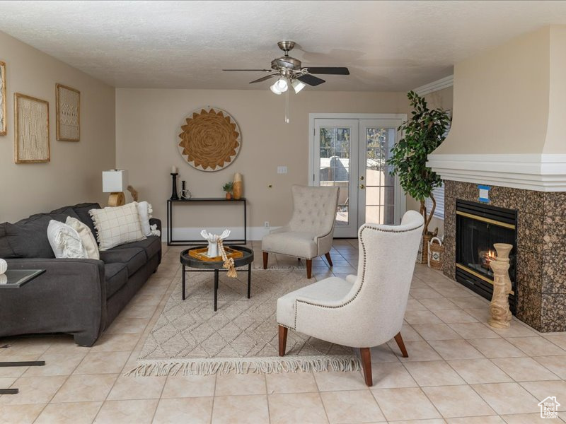 Living area featuring a ceiling fan, light tile patterned floors, and a high end fireplace
