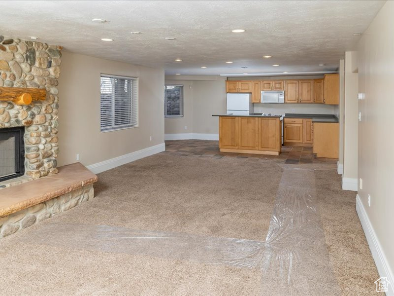 Kitchen featuring white appliances, carpet, open floor plan, recessed lighting, and dark countertops