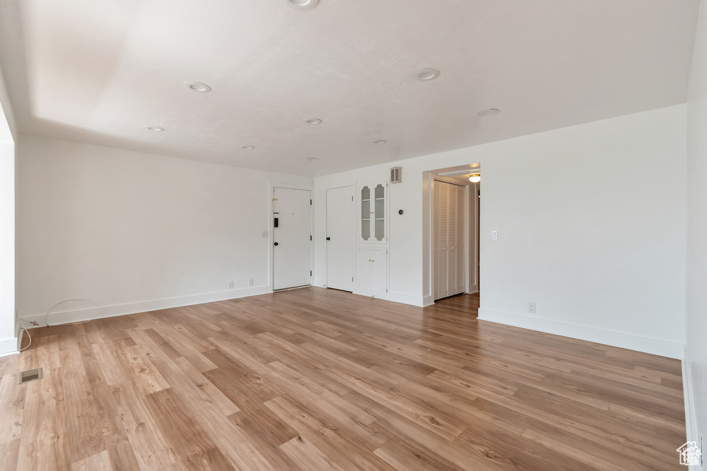 Empty room featuring light wood-type flooring, baseboards, and recessed lighting