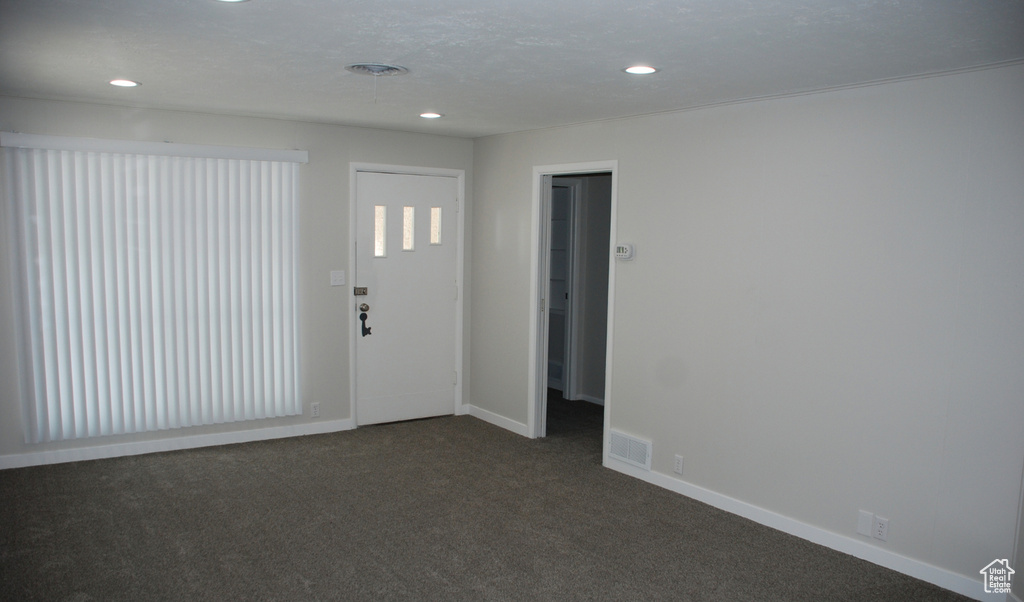 Foyer with recessed lighting, dark colored carpet, and baseboards