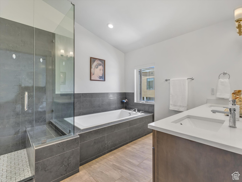 Bathroom featuring vaulted ceiling, a garden tub, a shower stall, and double vanity