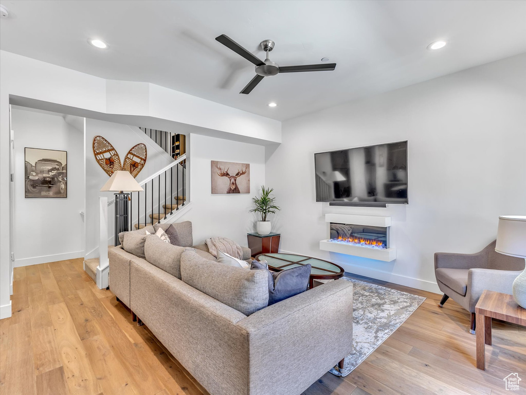 Living area featuring ceiling fan, stairs, wood finished floors, baseboards, and recessed lighting