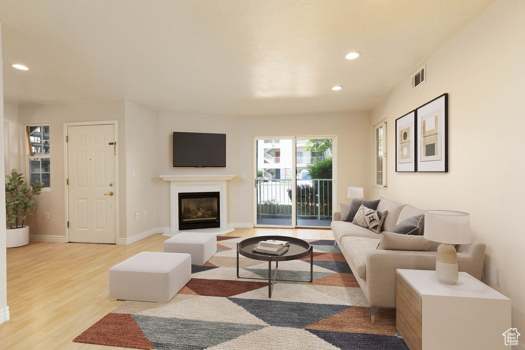 Living area featuring recessed lighting, light wood finished floors, a glass covered fireplace, and baseboards