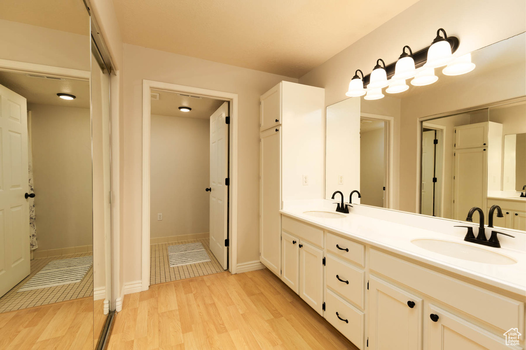 Bathroom featuring double vanity, wood finished floors, and baseboards