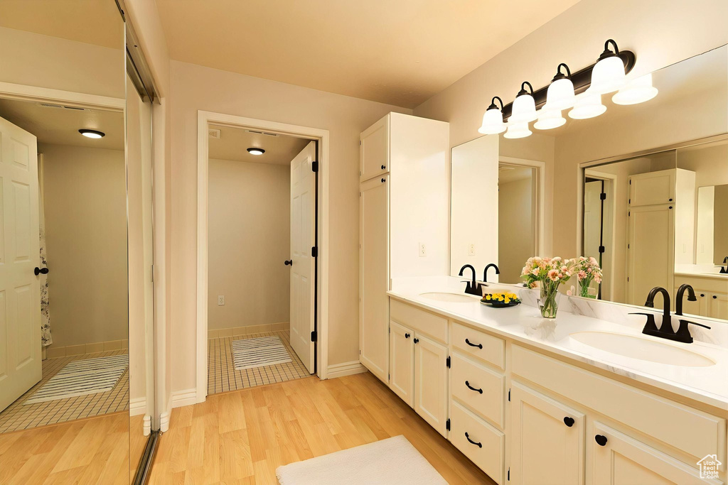 Bathroom with wood finished floors, double vanity, and baseboards