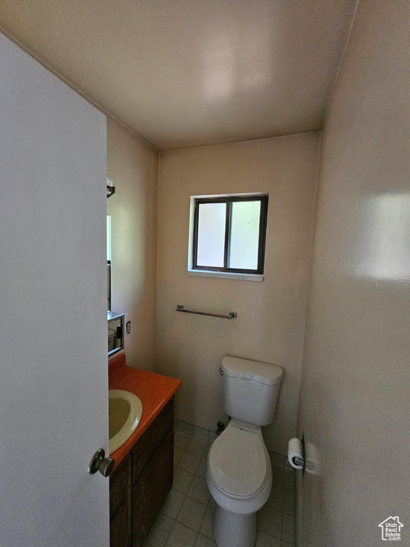 Half bath featuring toilet, vanity, and tile patterned flooring