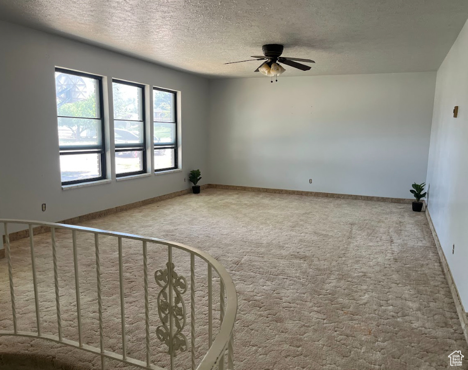 Carpeted spare room featuring a ceiling fan and a textured ceiling