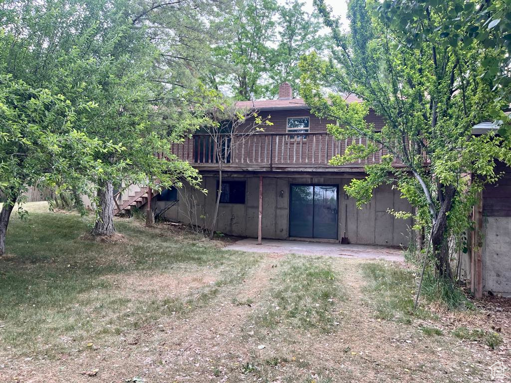Rear view of property featuring a deck, stairway, and a chimney