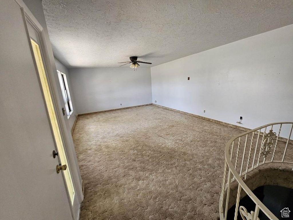 Carpeted spare room featuring ceiling fan, baseboards, and a textured ceiling