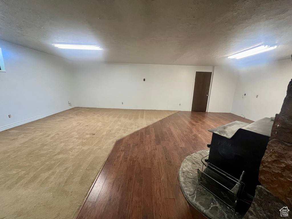 Below grade area featuring a wood stove, wood finished floors, and a textured ceiling