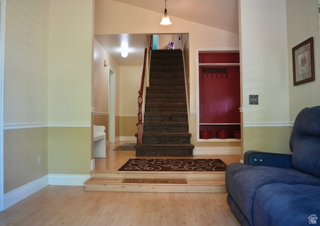Foyer featuring wood finished floors, stairs, vaulted ceiling, and baseboards