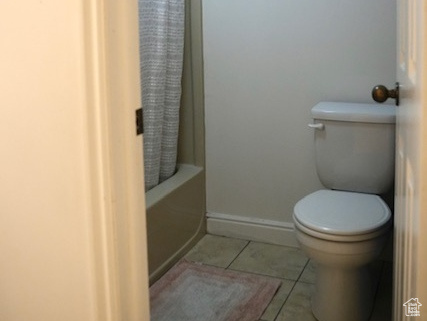 Full bath featuring toilet, tile patterned floors, and shower / bath combination with curtain