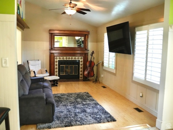 Living area featuring a ceiling fan, wood finished floors, lofted ceiling, and a fireplace