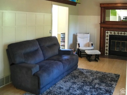 Living area with vaulted ceiling, ceiling fan, wood finished floors, and a fireplace