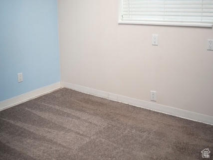 Unfurnished room featuring a paneled ceiling, dark colored carpet, and baseboards