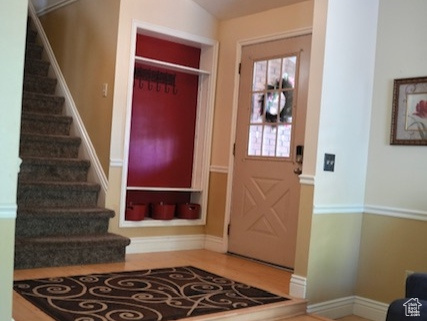 Foyer entrance featuring wood finished floors, stairs, baseboards, and vaulted ceiling