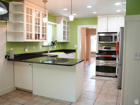 Kitchen with stainless steel appliances, a peninsula, dark countertops, a sink, and recessed lighting