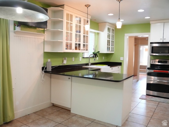 Kitchen featuring stainless steel appliances, dark countertops, a sink, open shelves, and radiator heating unit