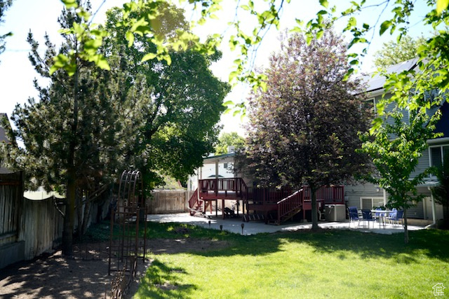 View of yard featuring stairs, a wooden deck, and a patio area
