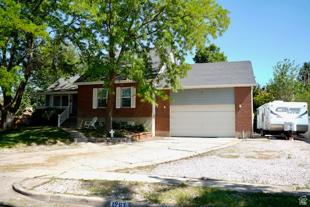 Ranch-style house featuring concrete driveway, brick siding, and a garage