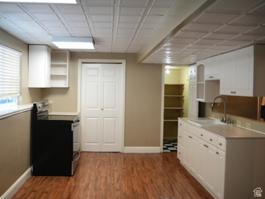 Kitchen with stainless steel range with electric stovetop, a sink, baseboards, open shelves, and dark wood-style floors