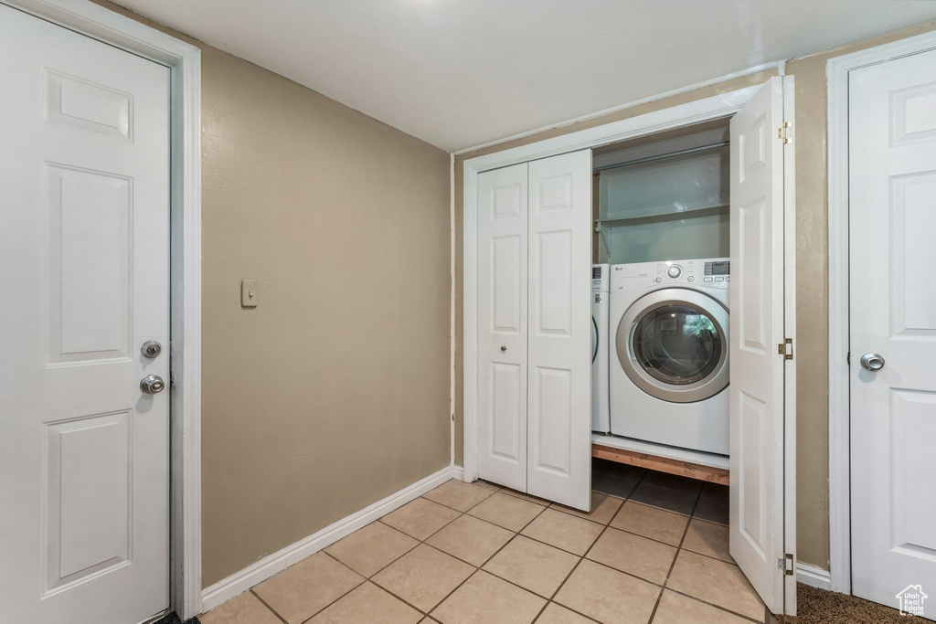 Laundry room with washer / clothes dryer, light tile patterned floors, and baseboards