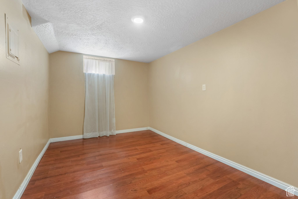 Spare room featuring a textured ceiling, wood finished floors, and baseboards