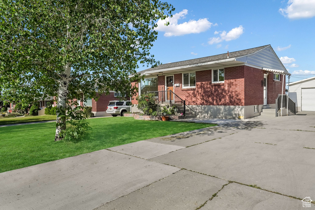 View of front of house with brick siding, driveway, and a front yard