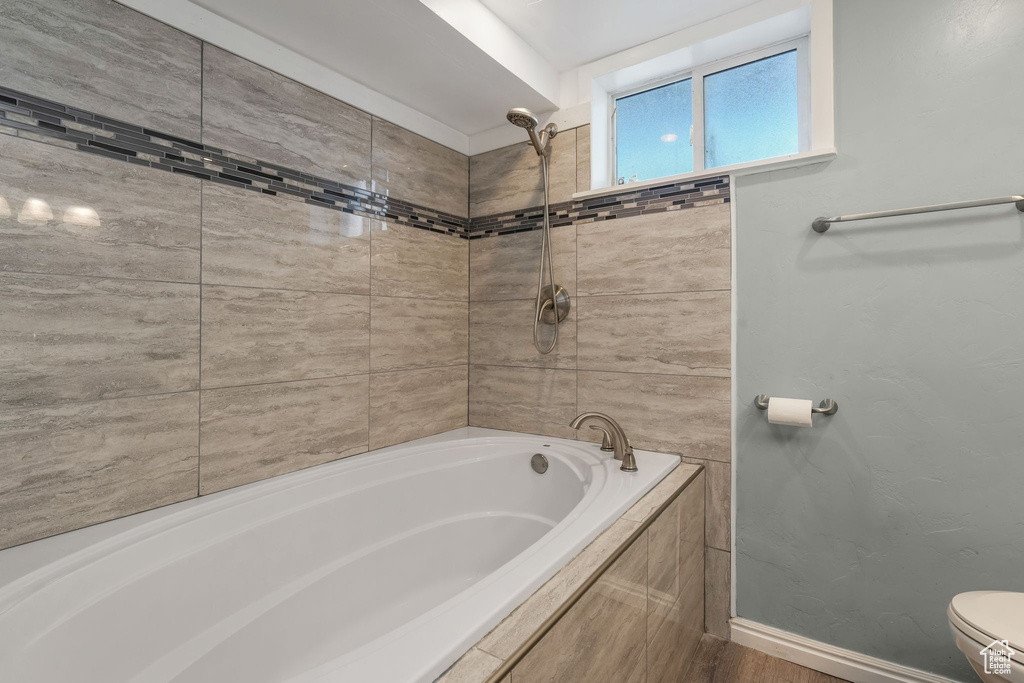 Bathroom with toilet, tiled shower / bath combo, and baseboards